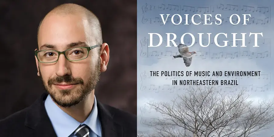 bald man with glasses in a suit with a book cover featuring a tree and a bird