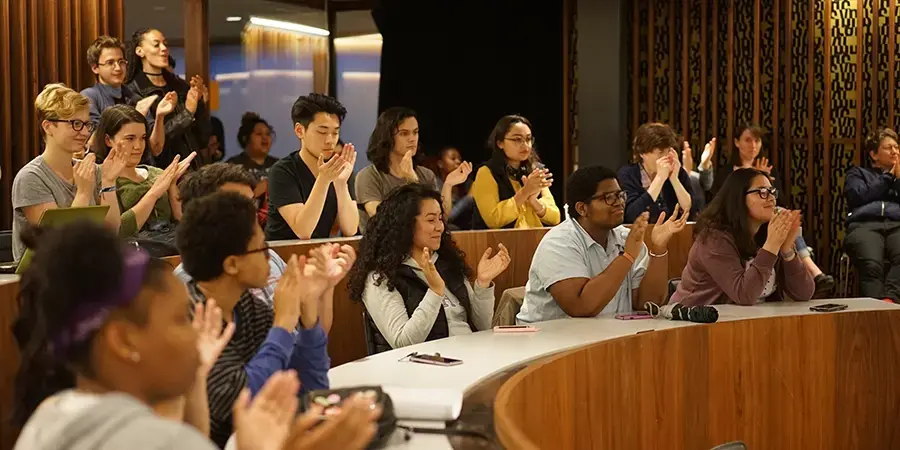 Group of students sitting in a tiered ring clapping