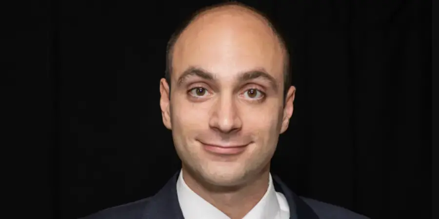 A bald man in a suit with a small smile on his face