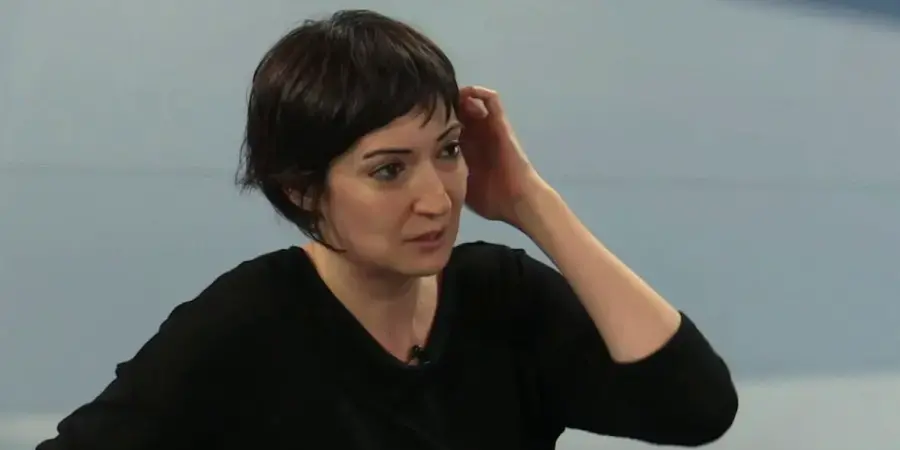 woman in black sweater against pale blue background