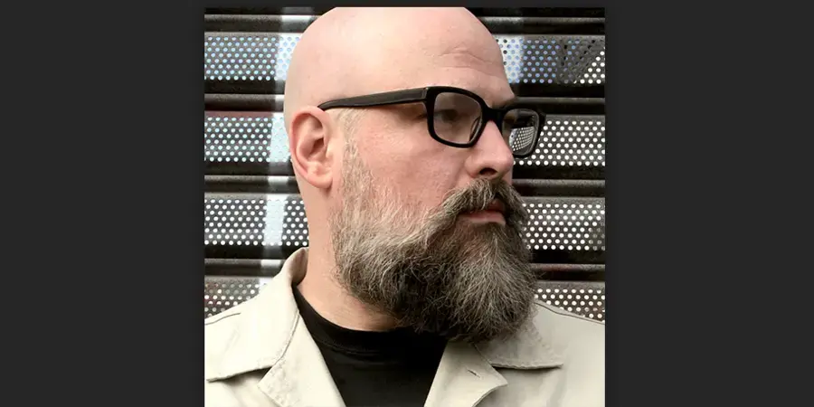 Bald man with glasses against striped background