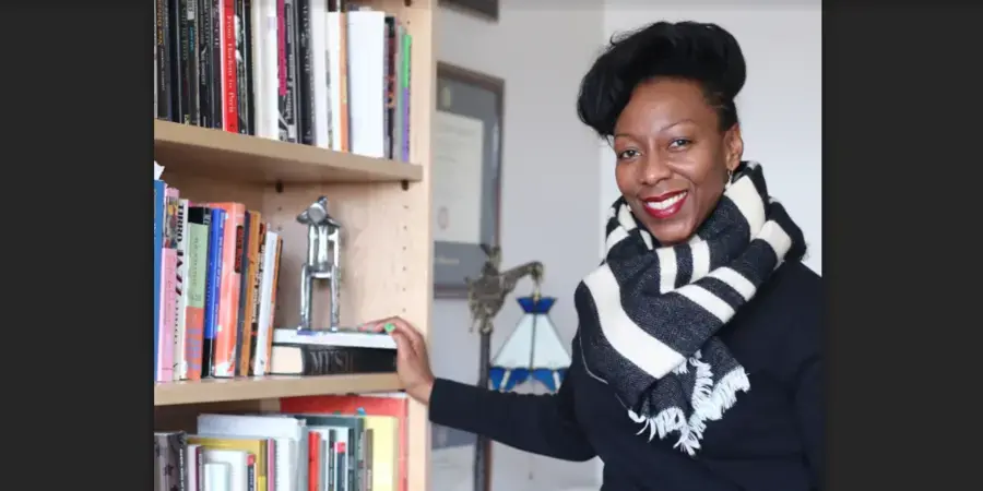 smiling woman in striped scarf beside a bookshelf