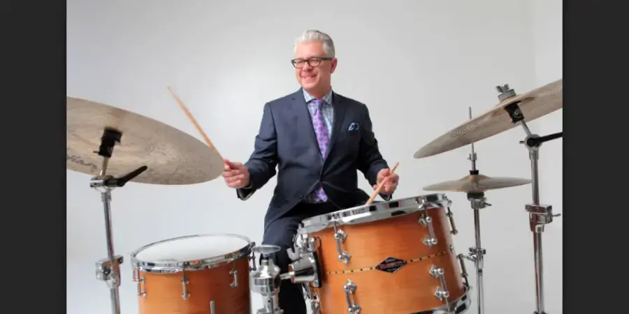 man in a suit playing a drum kit