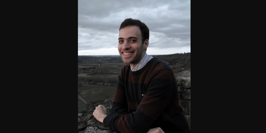 smiling man in a sweater above a bleak landscape