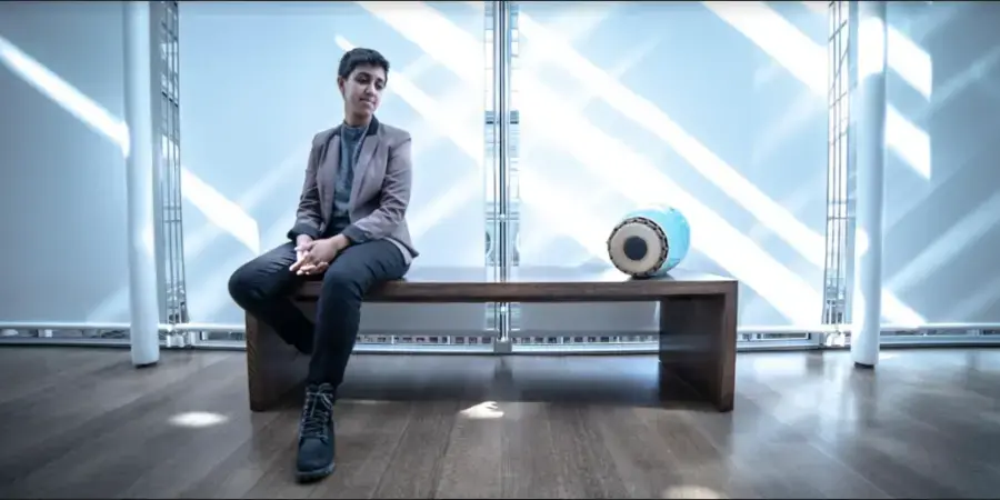 futuristic blue-toned photo of a young woman and a drum on a bench