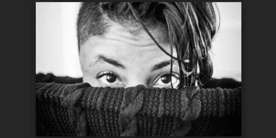 black and whit photo of the top of a head peaking out of a cloth basket