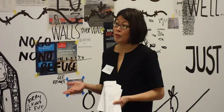 woman with short dark hair and glasses presenting