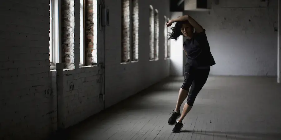 dancer, body twisted mid-move in an empty industrial space 