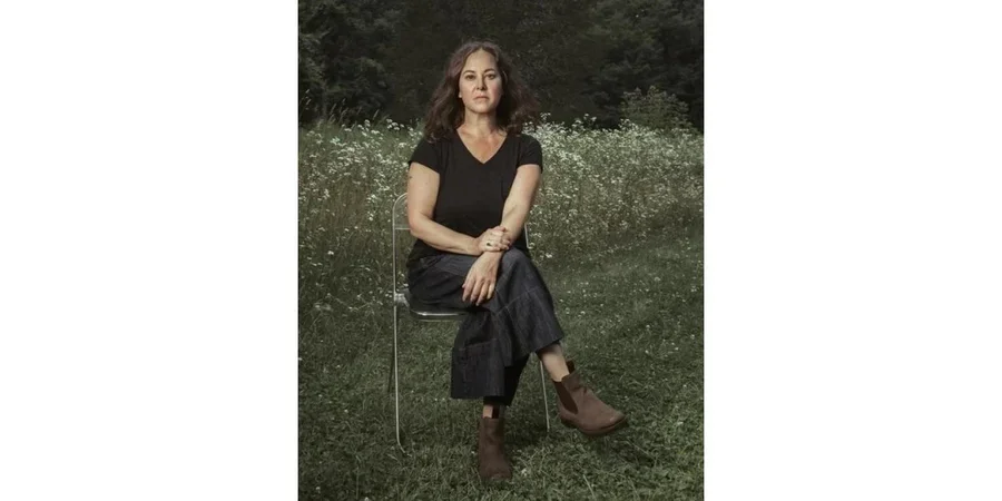 Lisa Olstein sitting in a folding chair on the grass