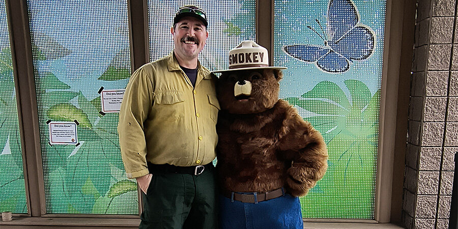 Tyler Briggs and Smokey the Bear against a flowery background 