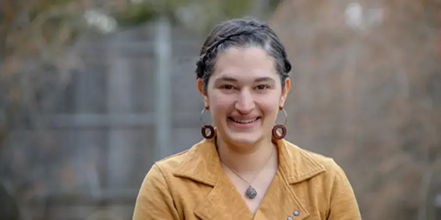 Woman in yellow coat in front of blurred background