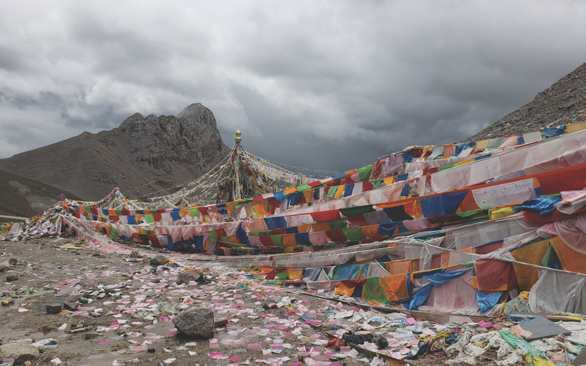 Many strings of colorful Tibetan prayer flags against grey mountains of rural Tibet
