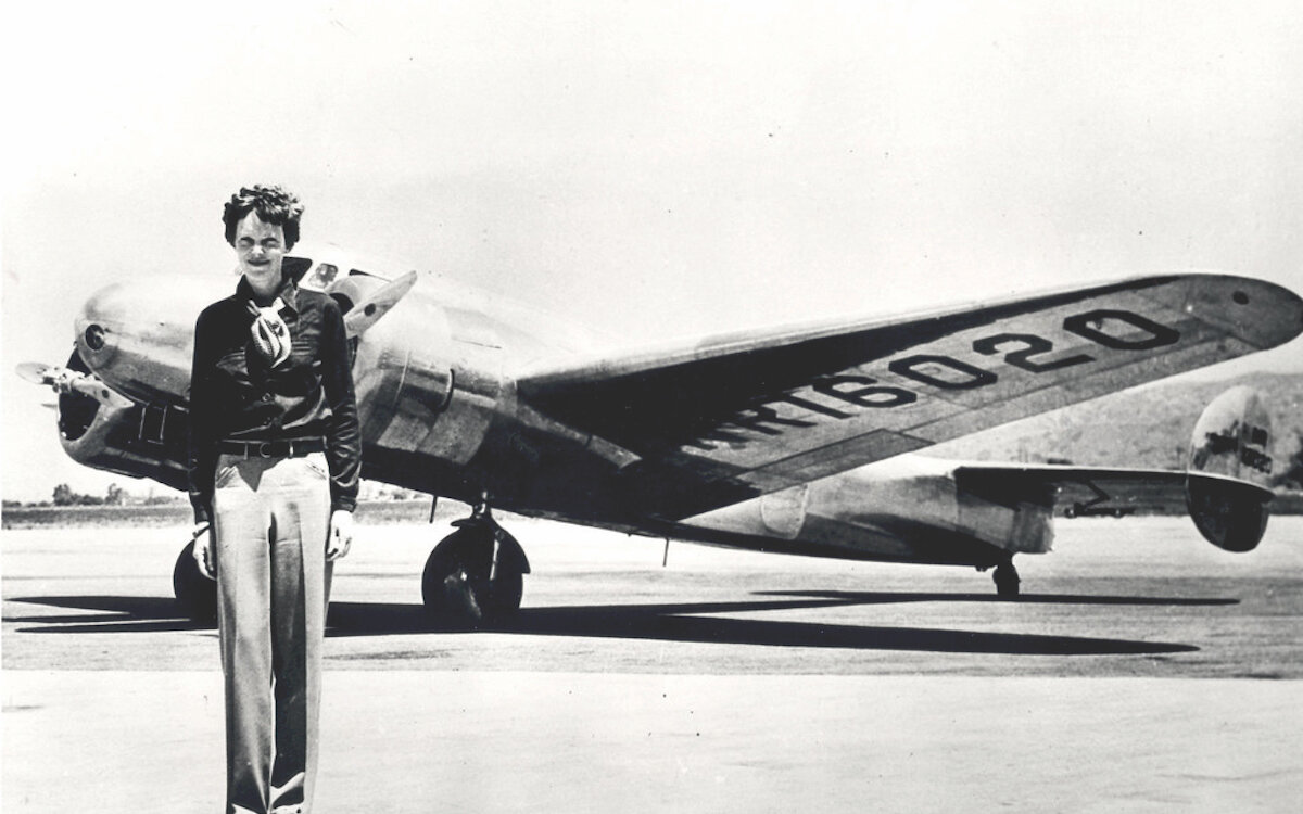 Amelia Earhart stands in front of her plane