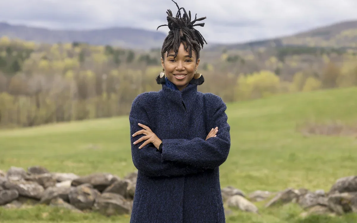 Outdoor portrait, with mountains and clouds in the background, of being, the artist formerly known as Kriss Mincey