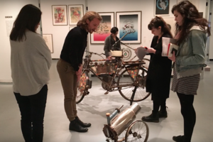 five people in a museum examining an art bike and art cannon