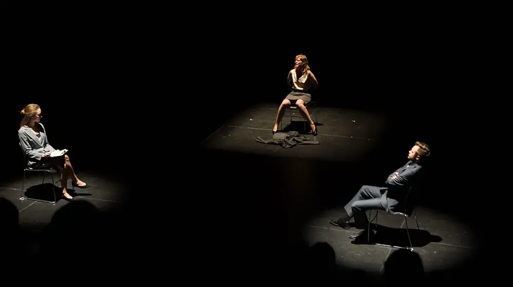Three actors seated on stage