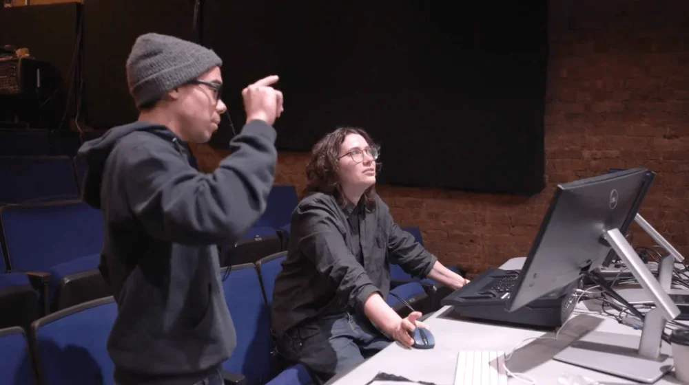 A student with their FWT mentor works on lighting in a control room