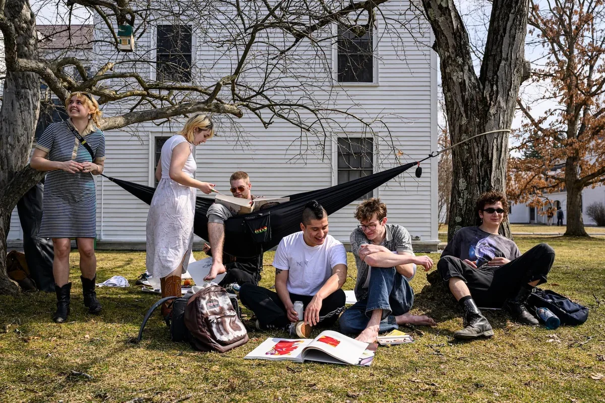 Bennington students read outside on a sunny day around a hammock