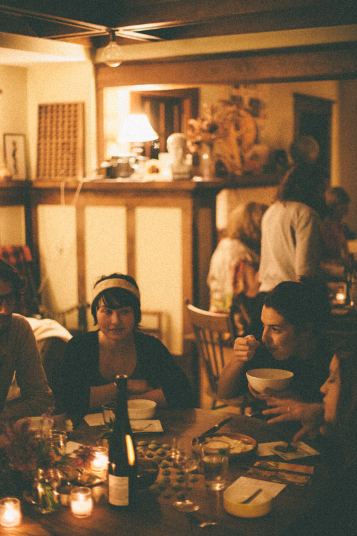 People sitting at a round table eating dinner in low light