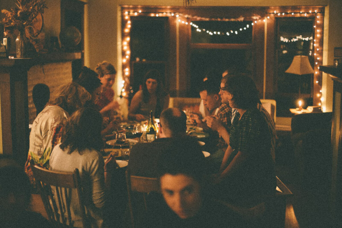 People sit around a round table eating dinner in low light