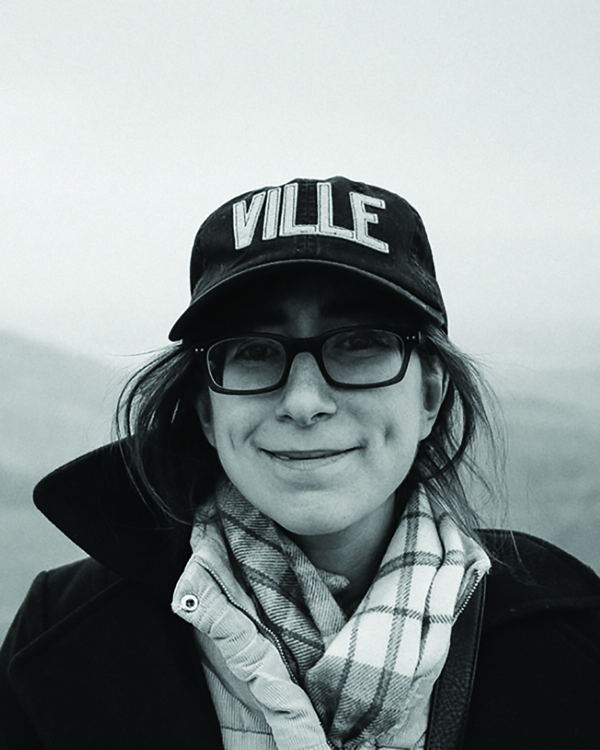 Audrey Shulman: woman wearing scarf, coat, glasses and hat that says Ville smiles at camera