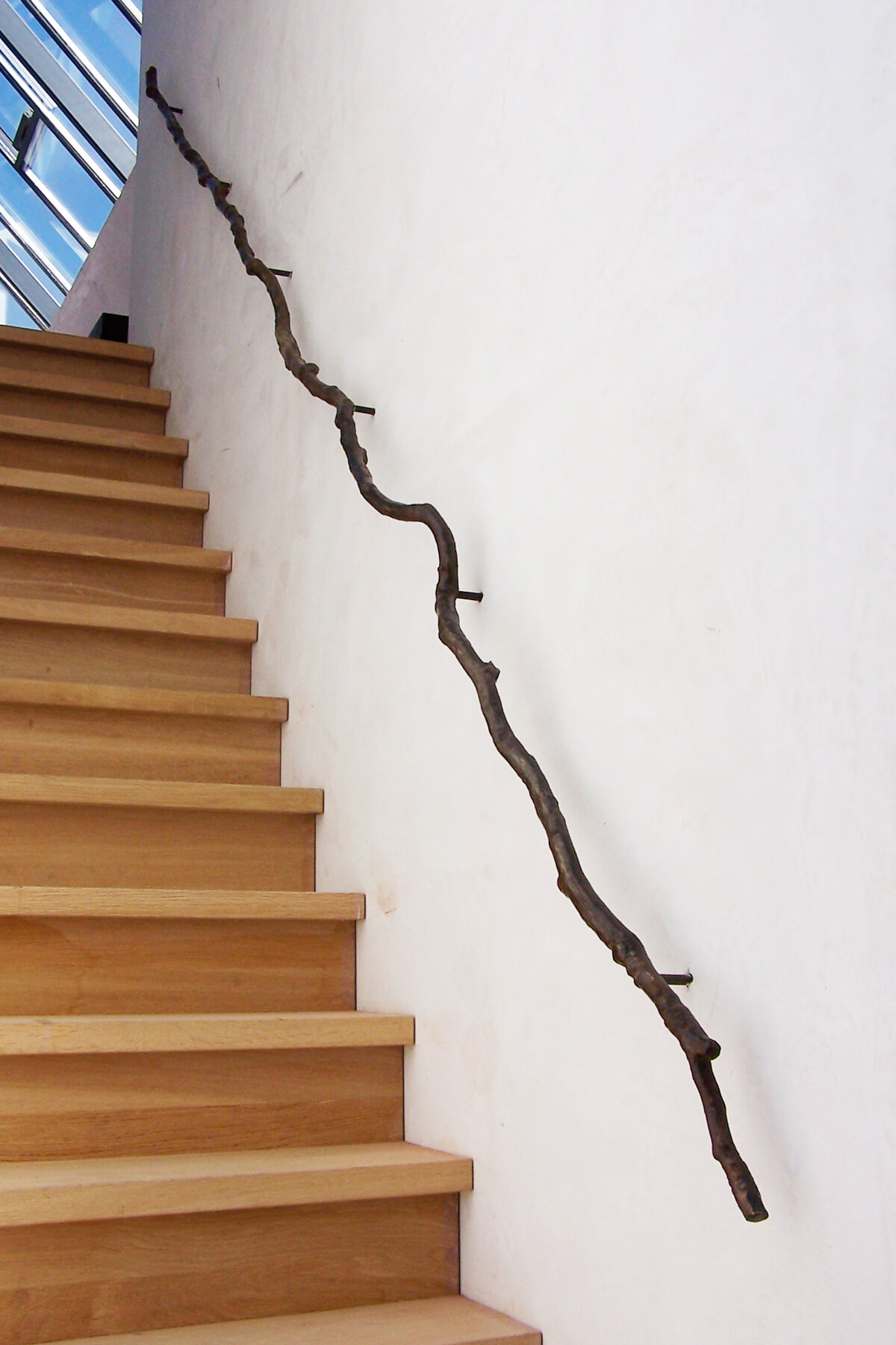 staircase with a long tree branch attached to the wall for a handle