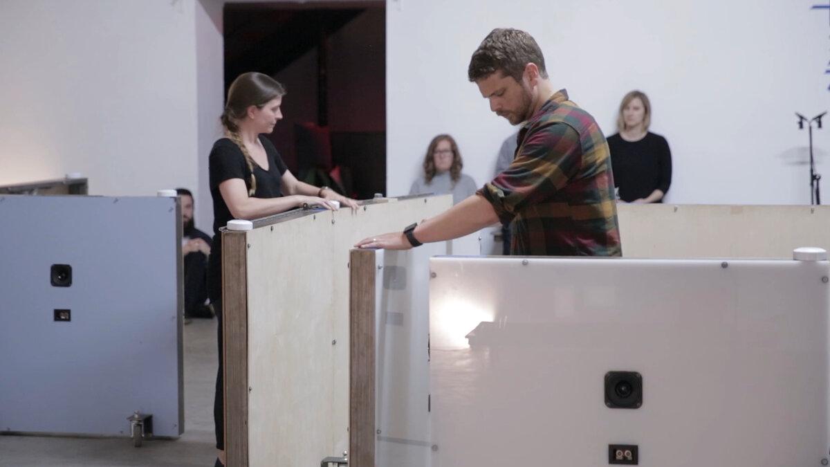 Two artists move two mobile half-sized walls