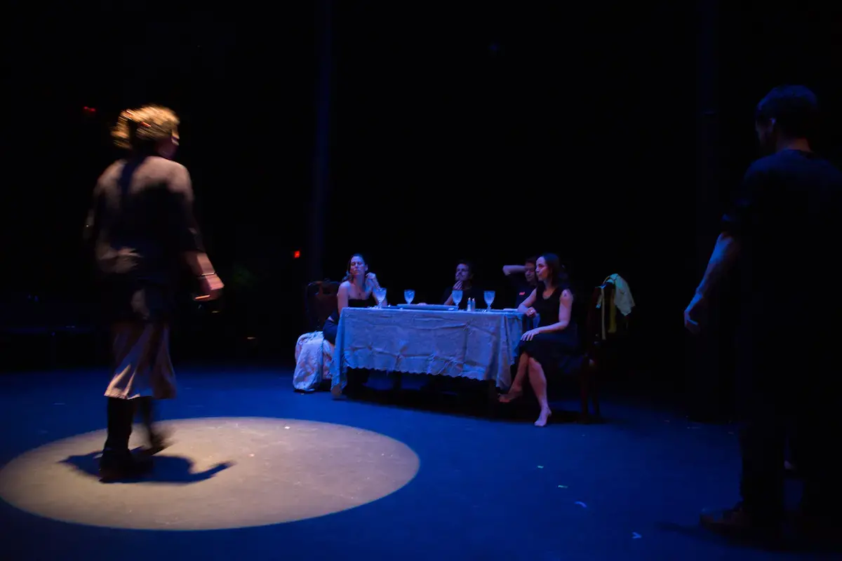 blue lit stage and spotlight on a female performer walking