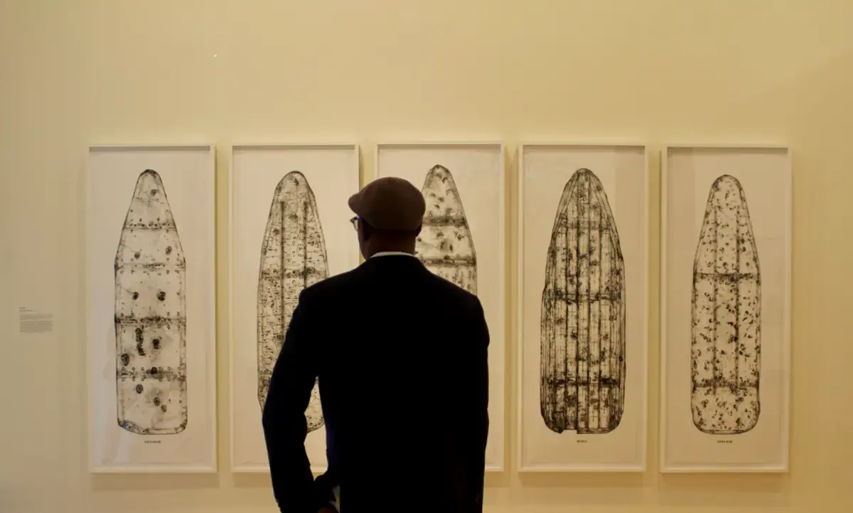 man dressed in black faces five rectangular art pieces