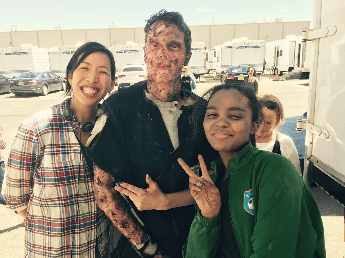 Janet Lin poses with two individuals, one in costume with visible injuries