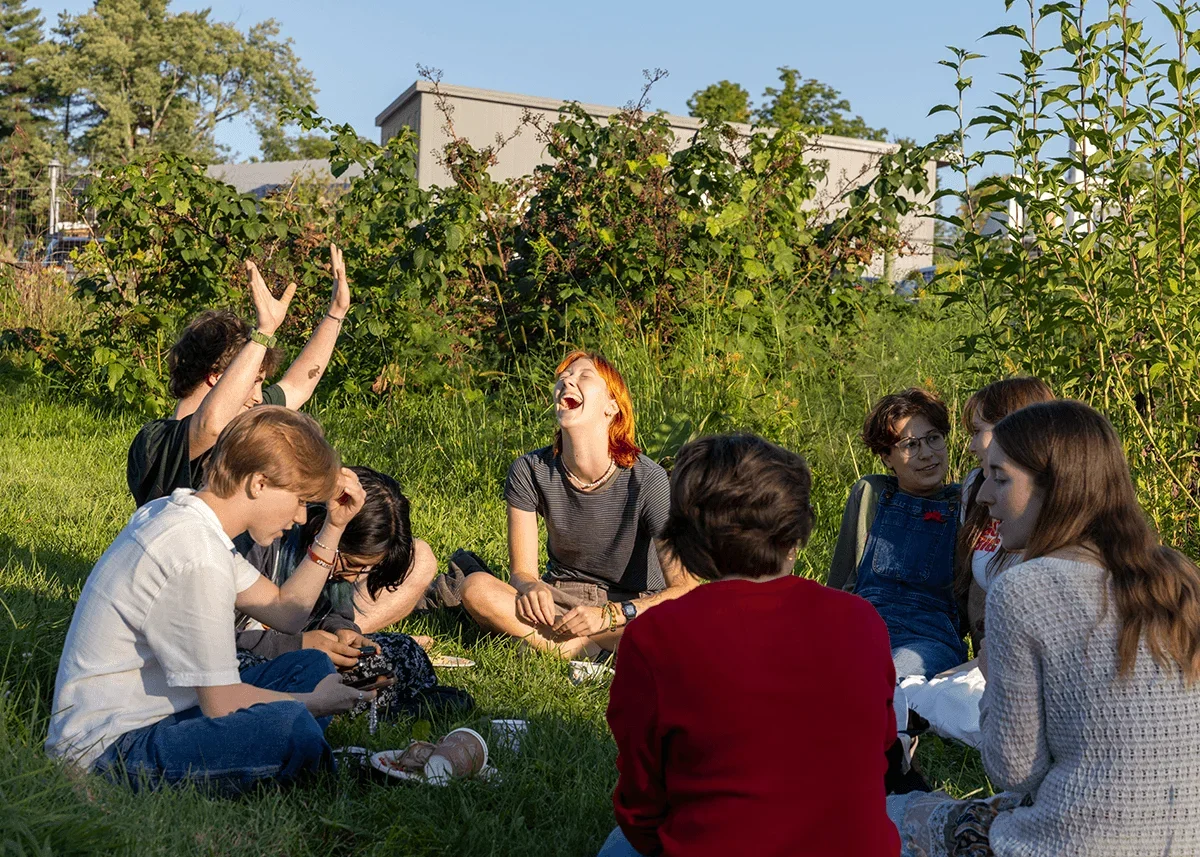 students sit in the grasses talking and laughing with one another