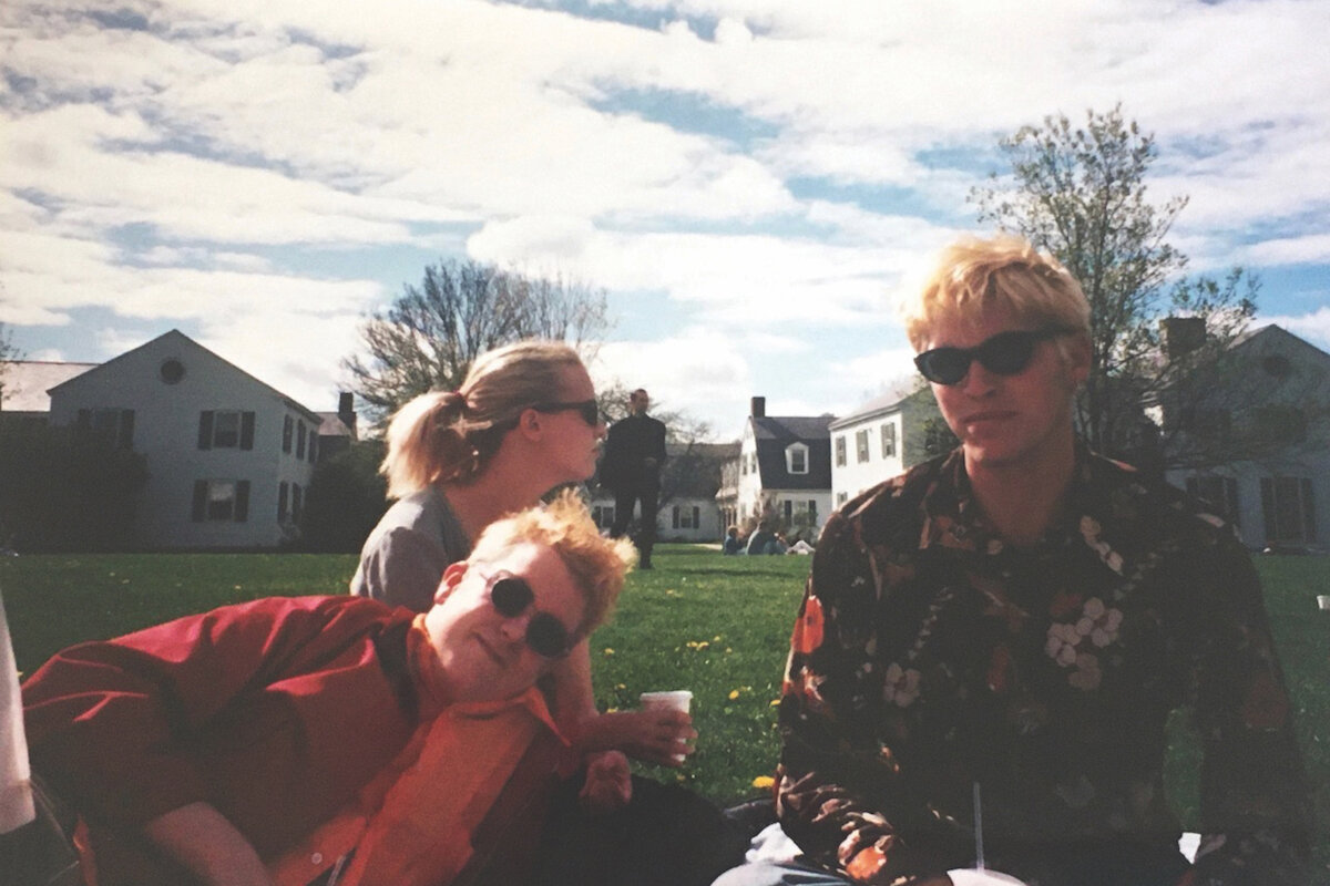 three students sitting on the lawn on a cloudy day