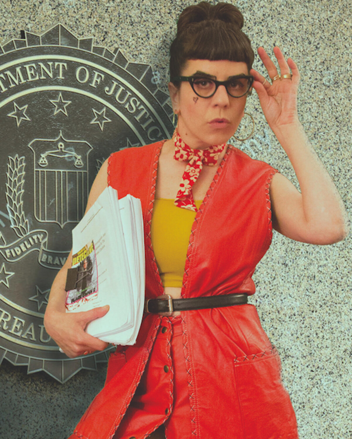 Liz, wearing a red dress, in front of the Department of Justice, holding her play