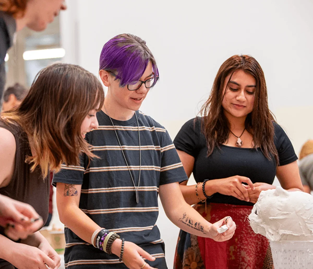 a student shows peers a sculpture