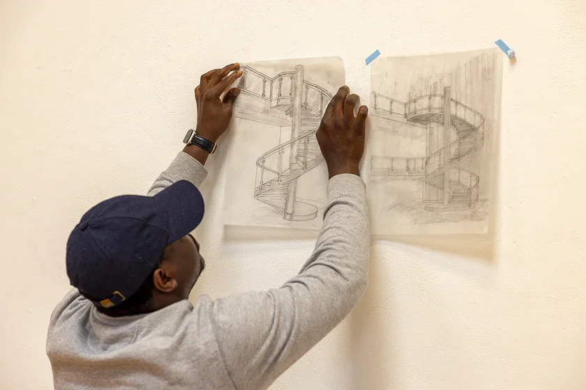 Student hanging drawing on a wall