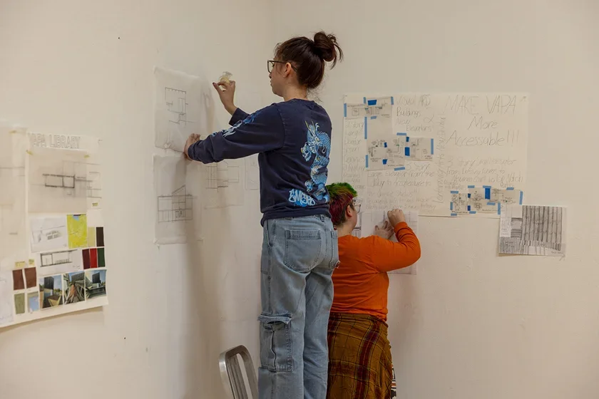 Student hanging drawing on a wall