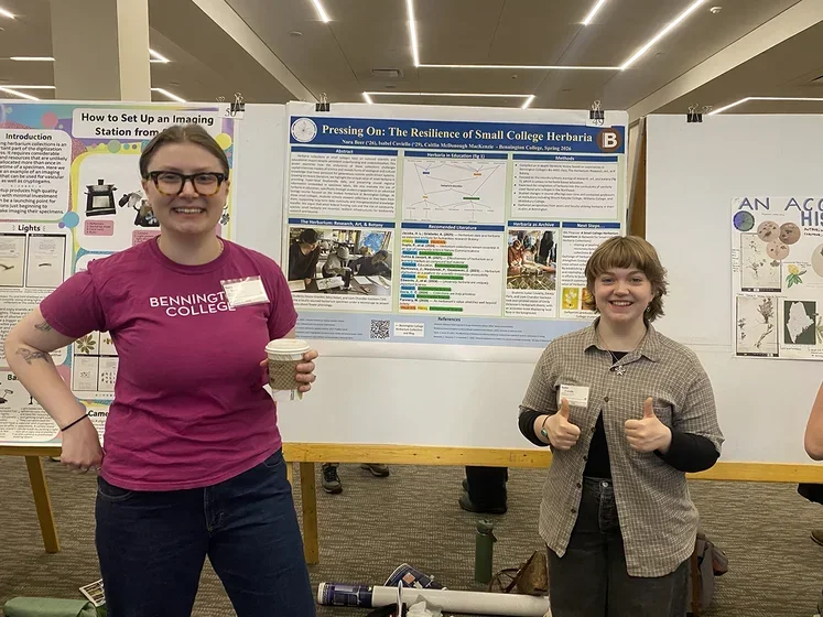 Image of two students in front of poster