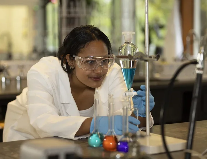 science student wearing a lab coat using chemistry equipment in a lab