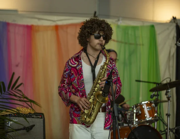 person in bright colored shirt playing saxaphone