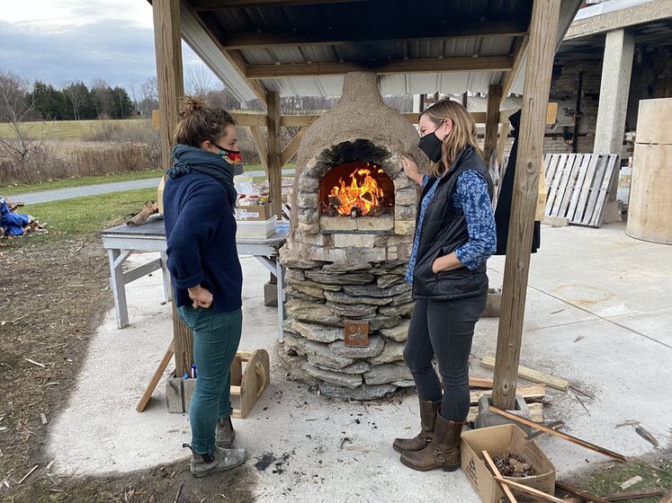 Image of two women in front of cobb oven