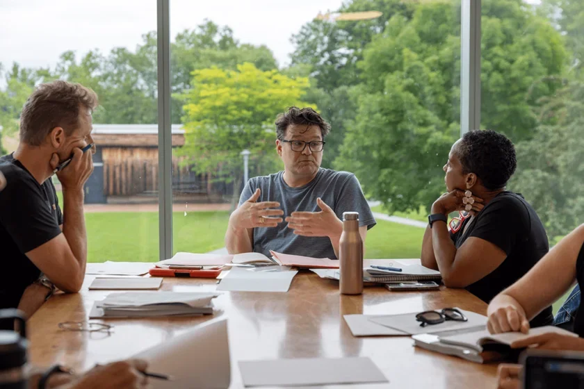 students sit at a table on campus and collaborate