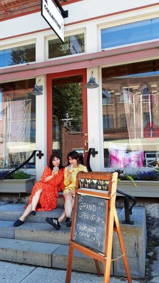 Two women sitting on shop stoop