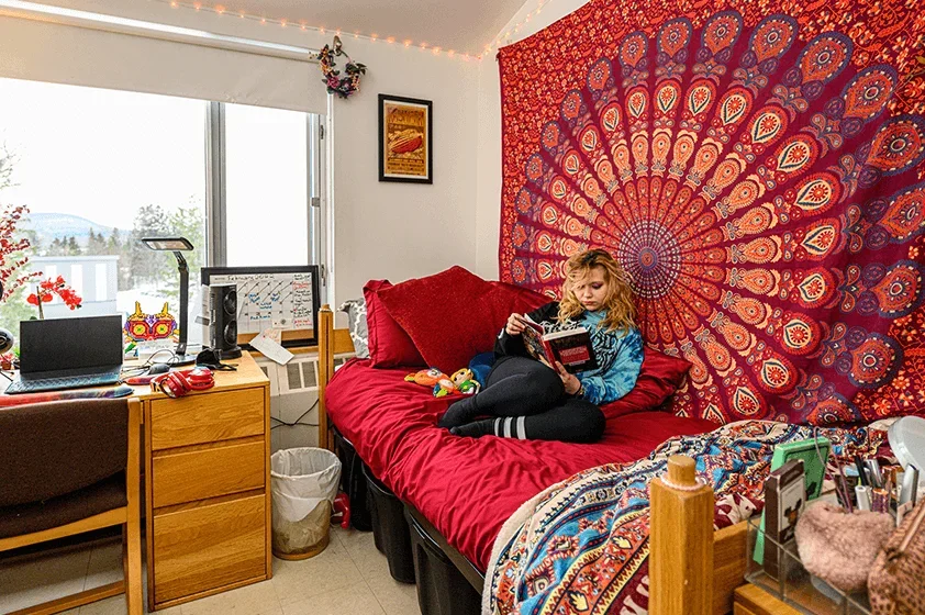 a student reads on their bed with a backdrop of a tie dyed cloth on the way